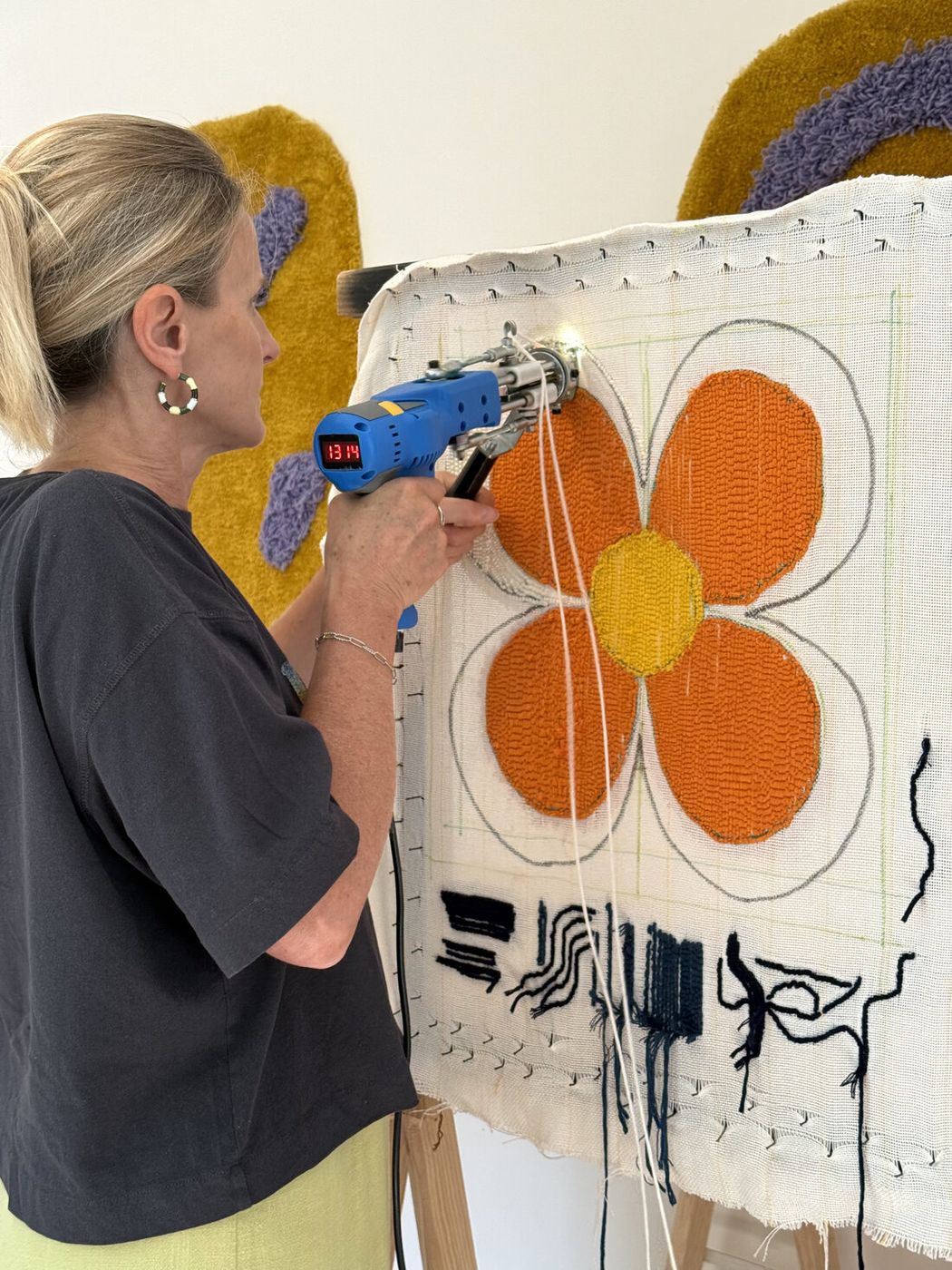 Participante tuftant une fleur orange pendant un atelier tufting à Lorient
