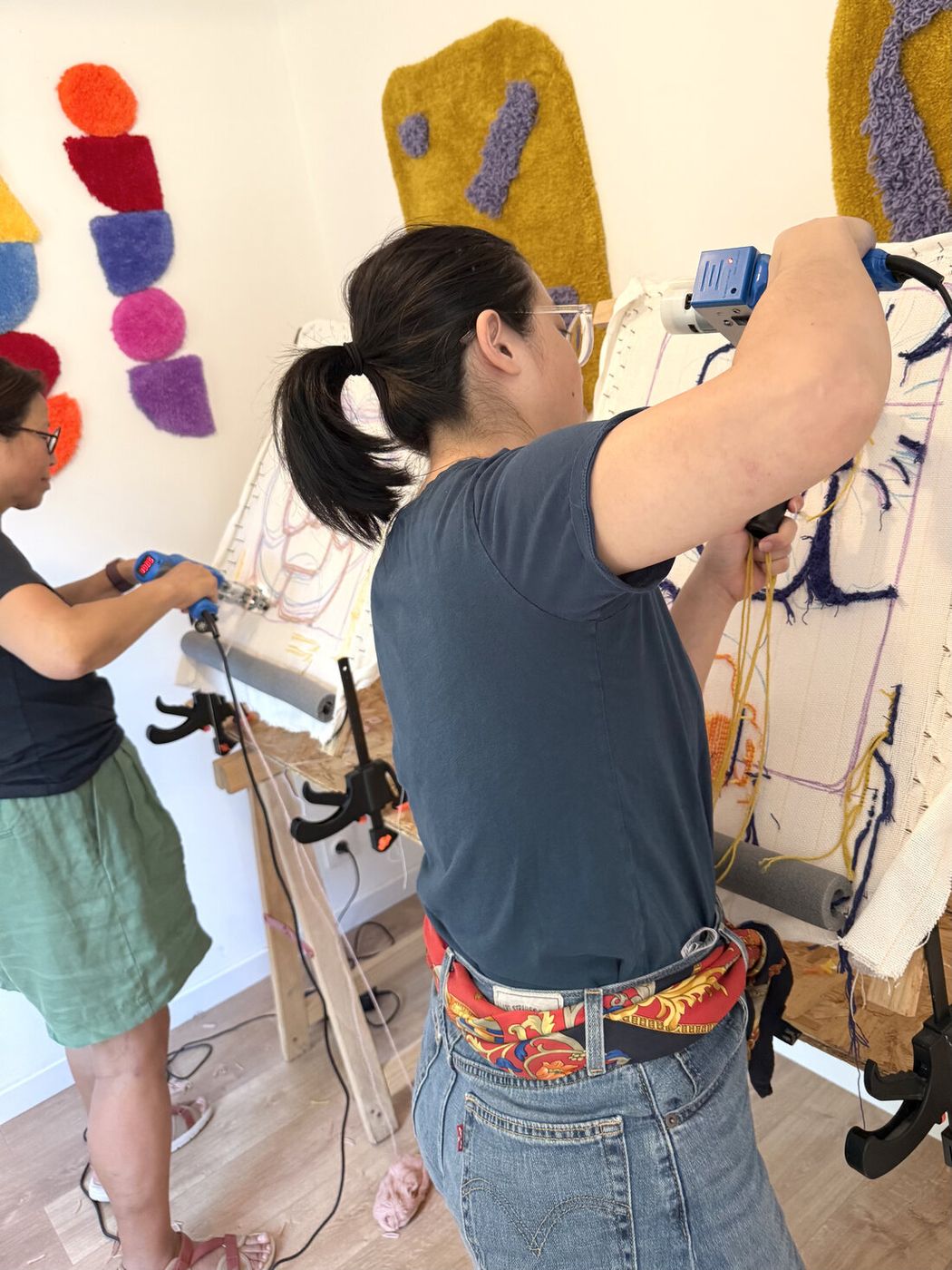 Deux participantes tuftent leur tapis au pistolet pendant un atelier au studio