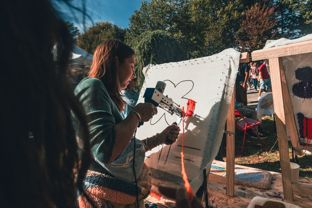 Une participante tufte un motif lors d'un événement en extérieur