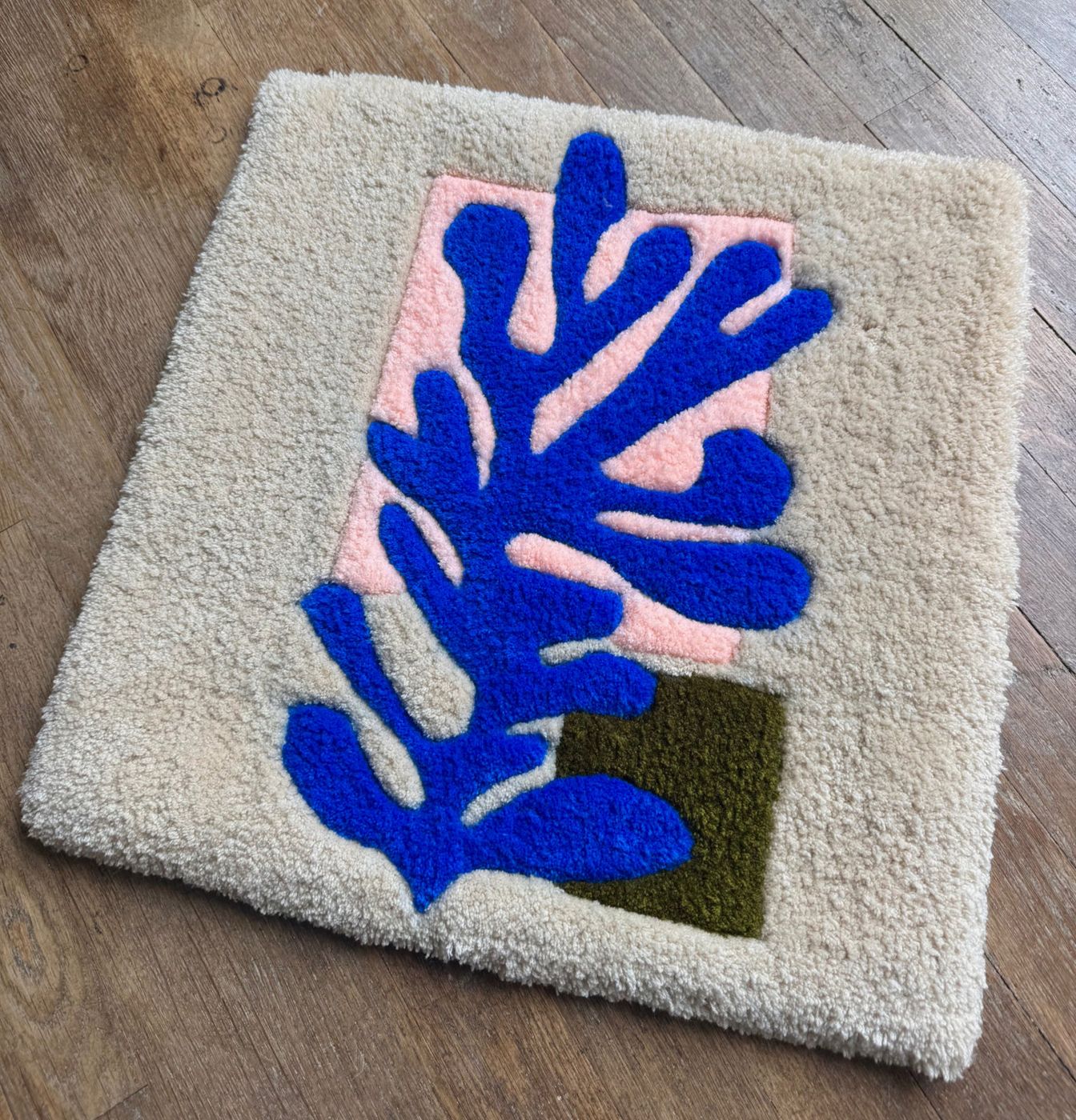 Tapis carré écru avec une algue bleue façon papier découpé