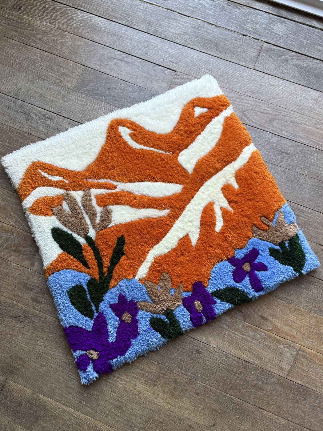 Tapis tufté en atelier : formes orange, fleurs violettes et bleues