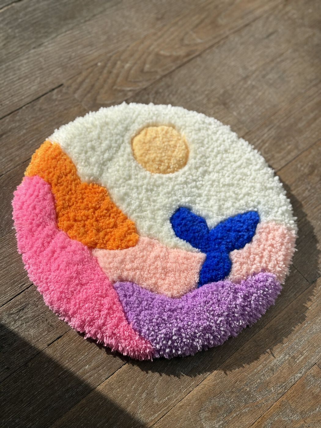 Petite pièce tuftée ronde : paysage rose, orange et violet avec soleil